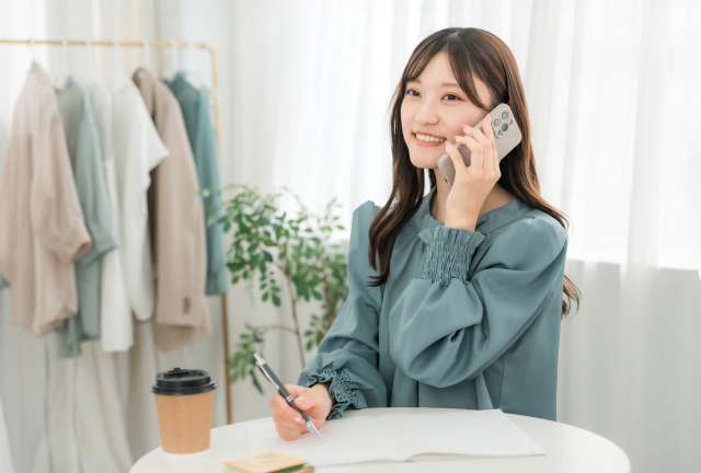 明るい笑顔で応募電話をかける女性。