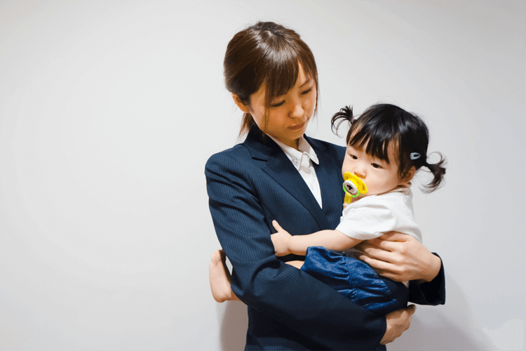 幼い子供を抱きかかえるスーツの女性