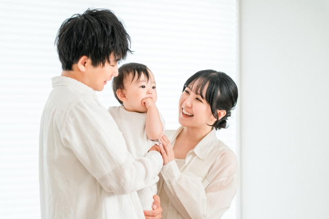 家で赤ちゃんを抱っこする若い夫婦